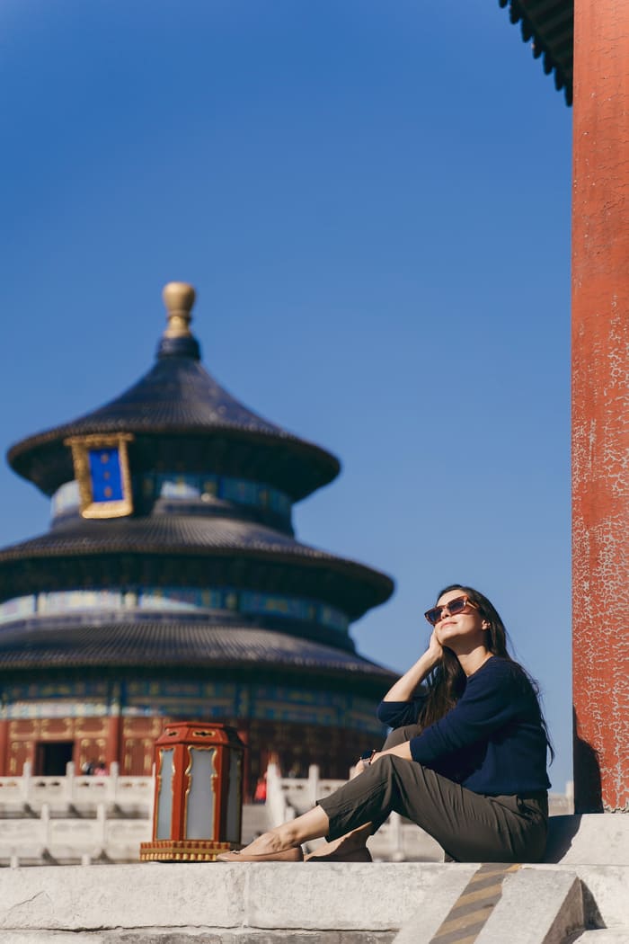 persona sentada frente a una construccion antigua de beijin, china